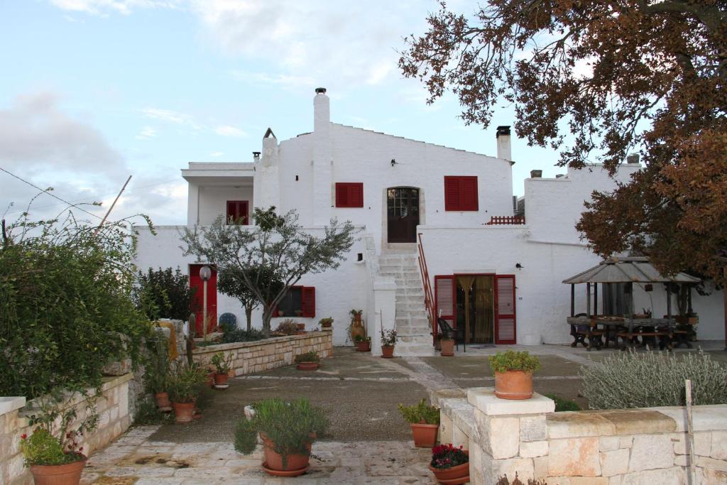 阿尔贝罗贝洛Agriturismo Laire Masseria的白色的房子,设有红色的窗户和庭院