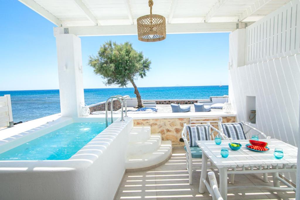 维查德Aegean Melody Suites & Villas的一个带浴缸和桌子的庭院以及大海