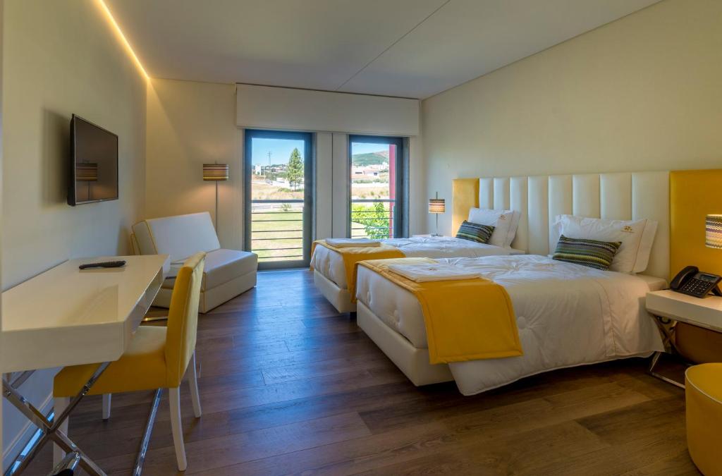 科维良Terrace Serra Hotel的酒店客房设有两张床、一张桌子和一张书桌。