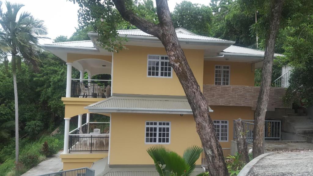 马埃岛Anse Royale Bay View Apartments的前面有树木的黄色房子