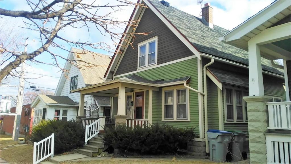 密尔沃基Comfortable 3 BR Craftsman Bungalow in Milwaukee's Bay View Neighborhood的绿色房子,有灰色的屋顶