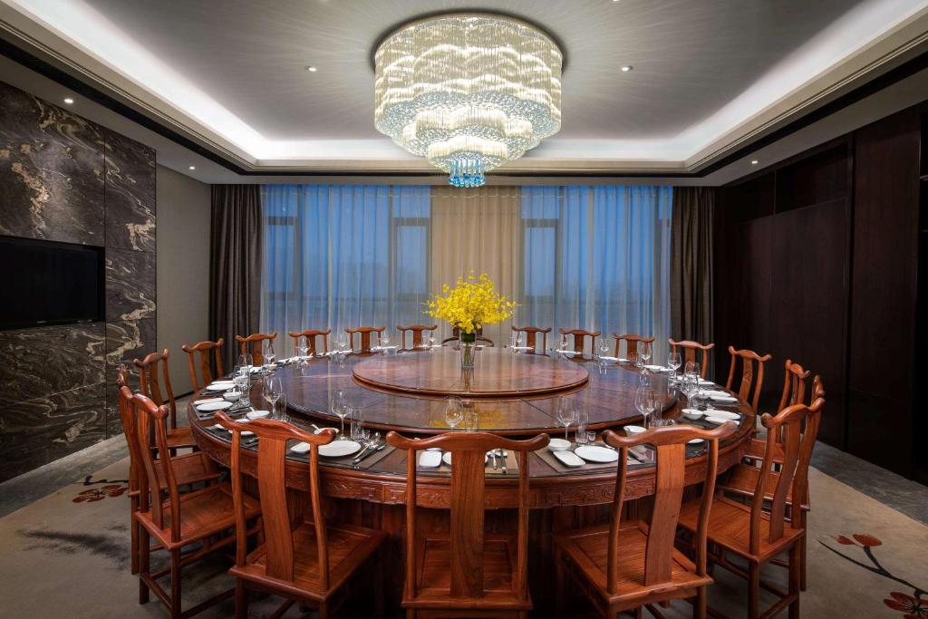 新郑郑州景瑞华美达酒店的大型用餐室配有大桌子和椅子