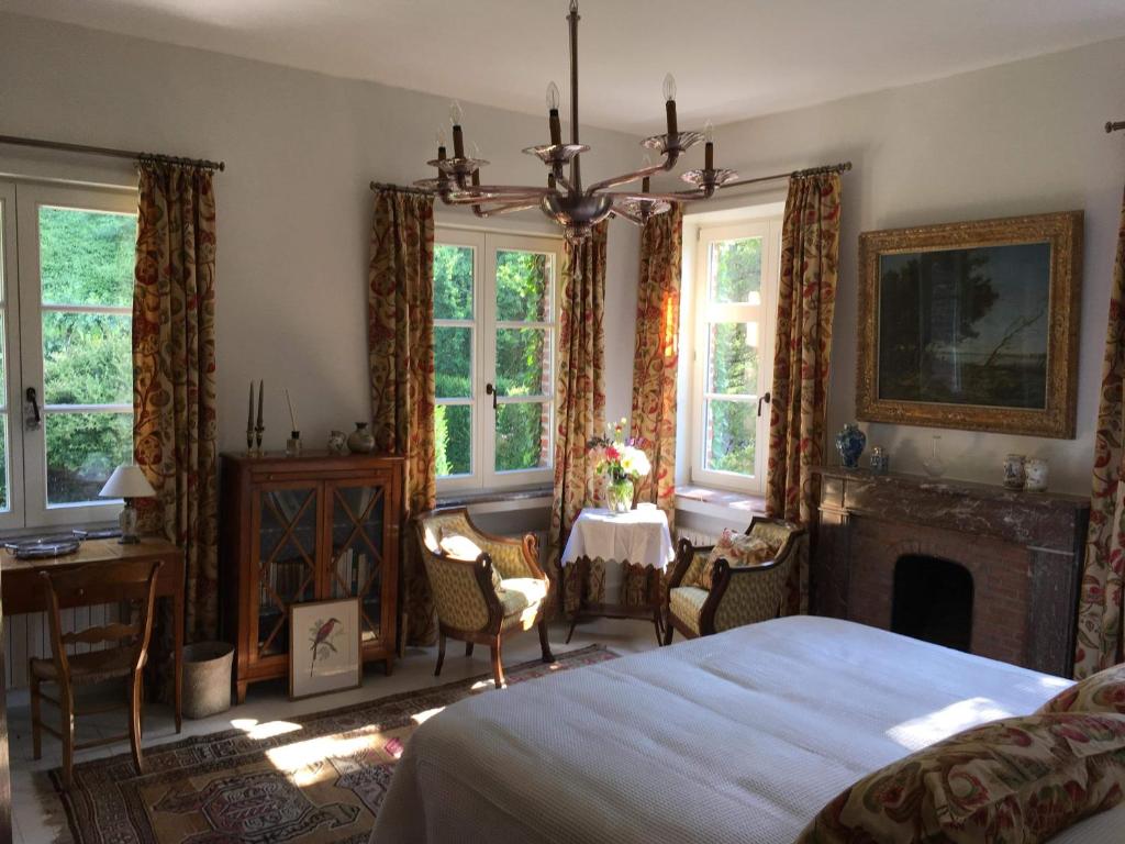 蒙斯Le Bocage Fleuri的一间卧室配有一张床、一个壁炉和一张桌子