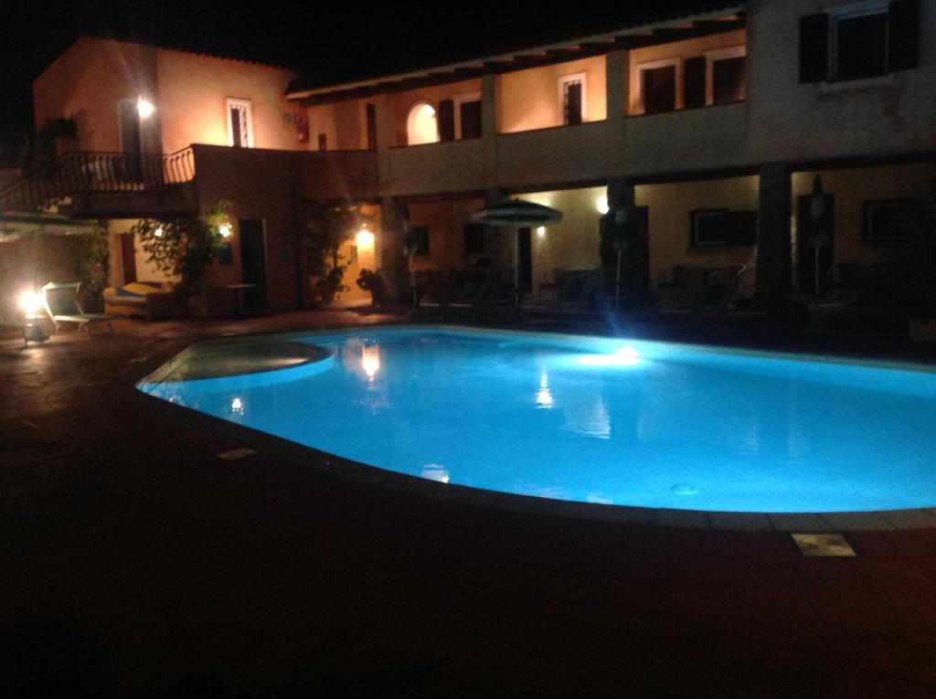 巴哈撒丁岛吉美拉别墅酒店的一座大型蓝色游泳池,在晚上在大楼前