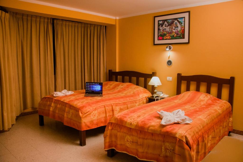 特鲁希略Hotel Amoretto的酒店客房设有两张床,上面有笔记本电脑
