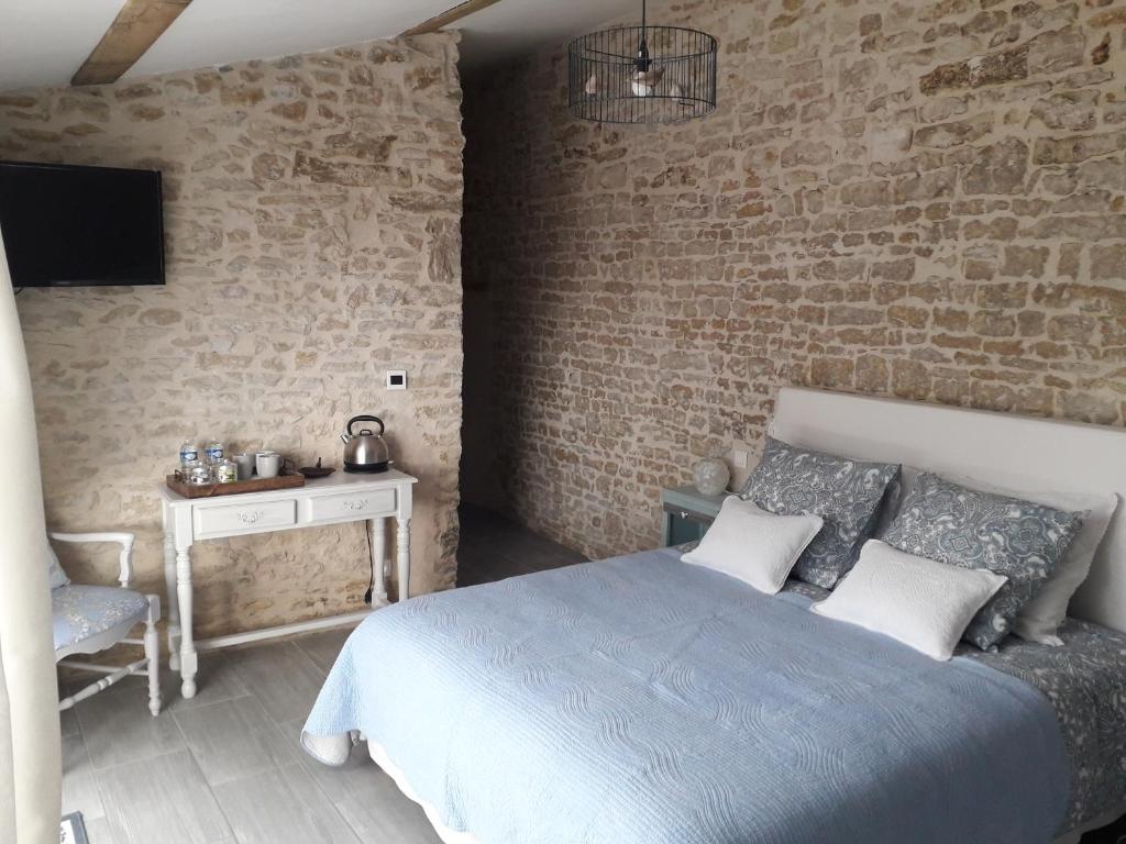 Bazoges-en-Paredsl' Oiseau Bleu的一间卧室设有一张床和砖墙