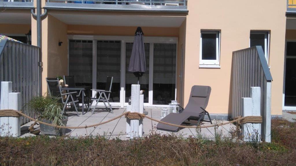 格拉尔-米里茨Ferienwohnung B4 Haus Elmsfeuer的庭院里摆放着一对椅子和一把遮阳伞