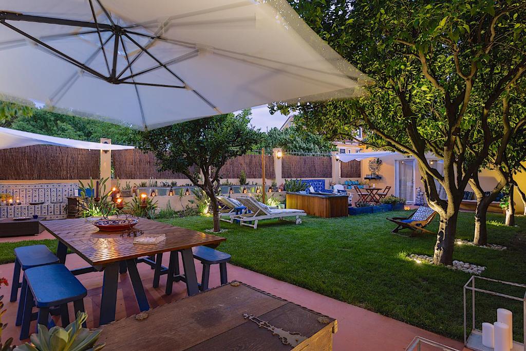 里斯本Geronimo Guest House Belém的庭院配有桌椅和遮阳伞。