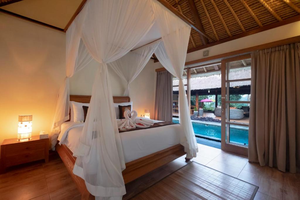 乌布Ubud Serendipity Villa的一间卧室设有天蓬床和一个游泳池
