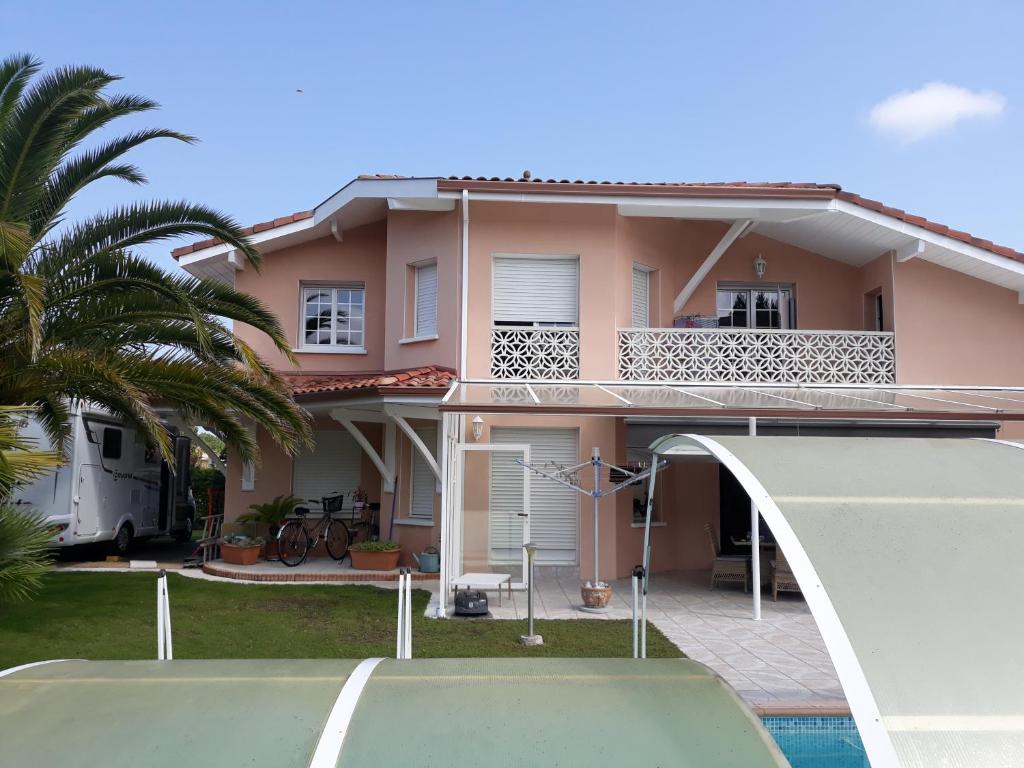 卡布勒通CHEZ MARTINE Appt climatisé 2 Chambres的粉红色的房子,前面有一个游泳池
