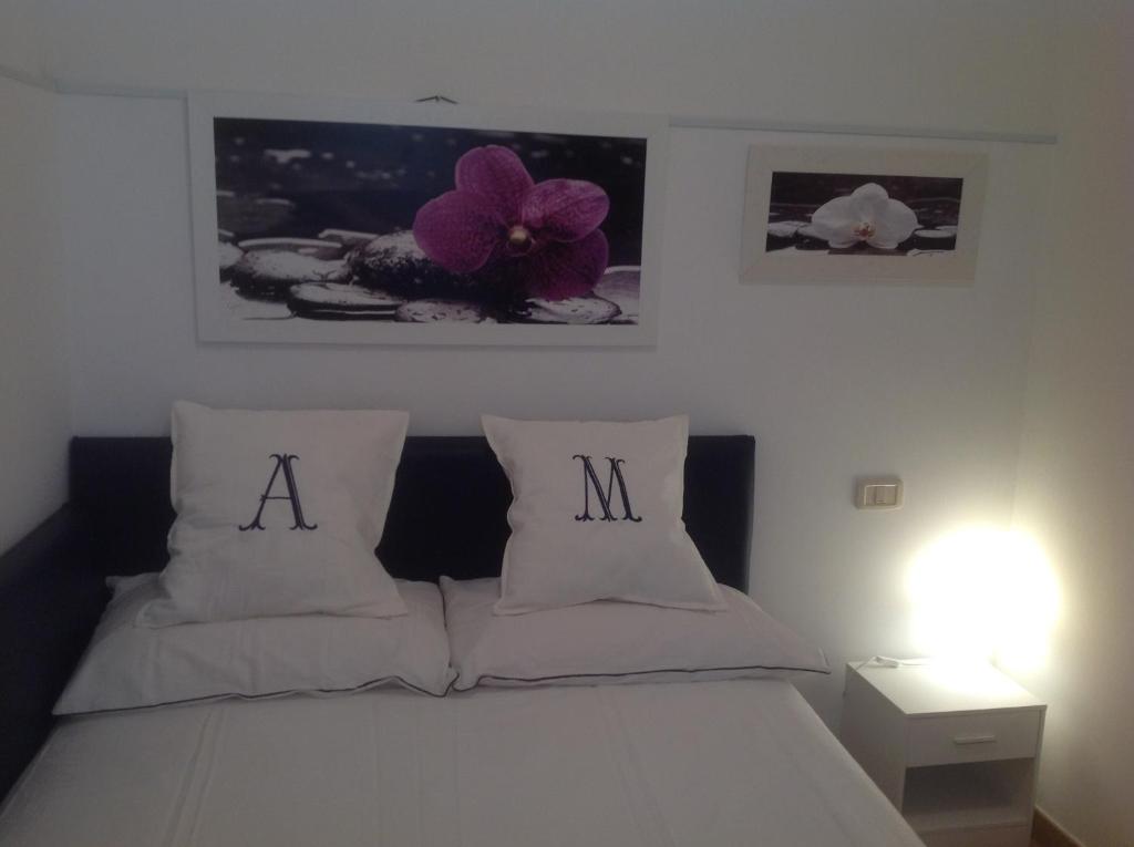 西维尔诺瓦·马尔凯Appartamento Manuela的一张带两个枕头的白色床,字母a和m