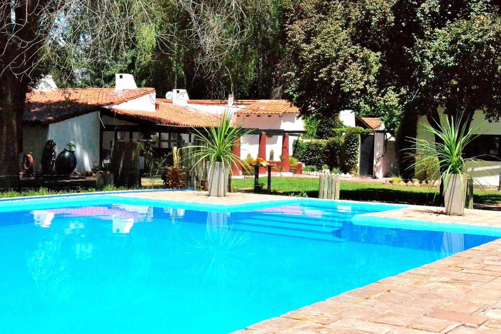 Eugenio Bustos拉西莉亚乡村民宿的蓝色的游泳池,后面有房子