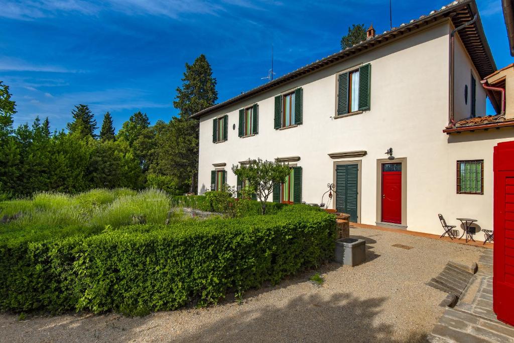 斯特拉达Agriturismo Villa Ulivello in Chianti的一间白色的房子,有红色的门和树 ⁇ 
