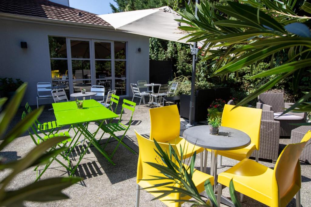 伊格涅南里昂 - 圣皮埃尔普瑞米尔经典酒店的庭院设有黄色的桌椅和雨伞。
