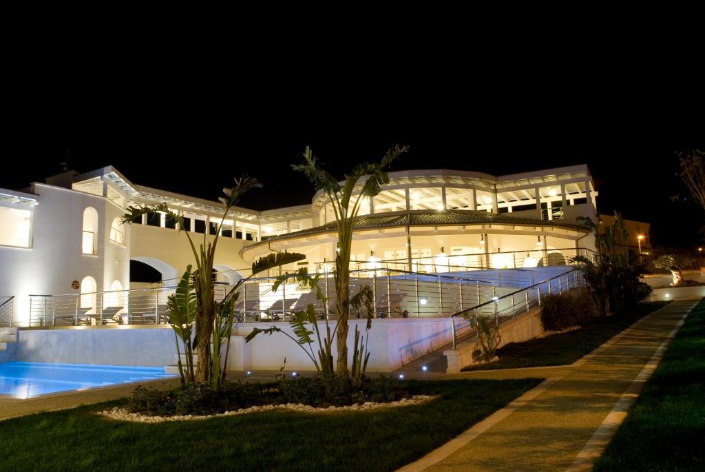 斯佩隆加嘉尼米德酒店 的一座白色的大建筑,晚上有游泳池
