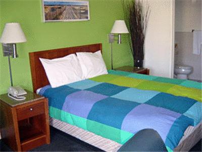 红木城红木城西阔尔宾馆的一间卧室设有一张色彩缤纷的床和绿色的墙壁