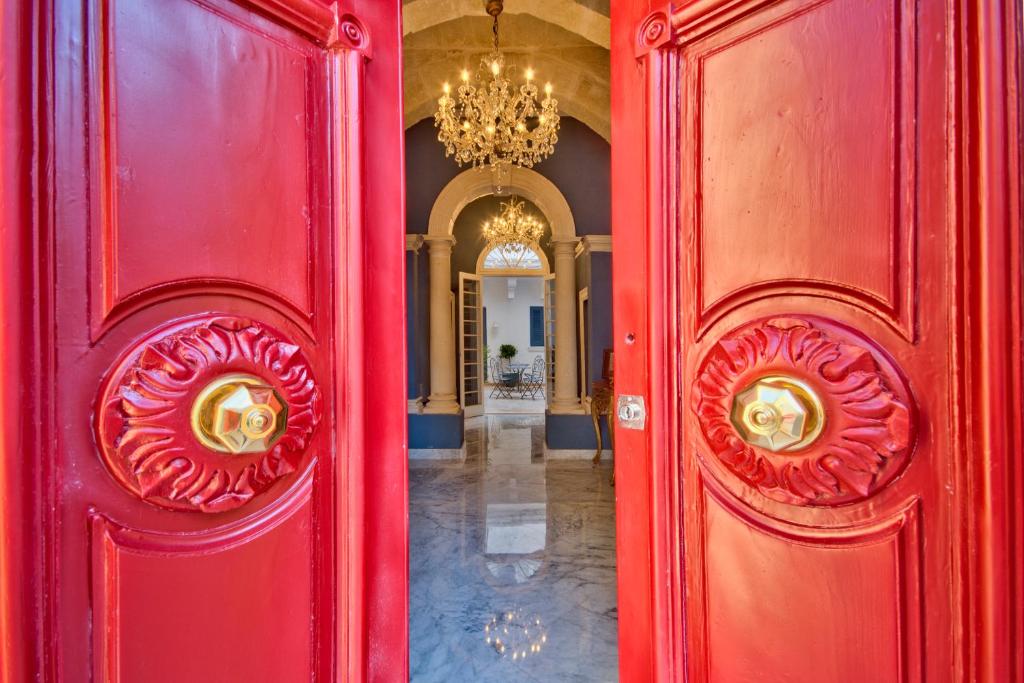 莫斯塔Julina Boutique Living的一道红色的门,通往带吊灯的走廊
