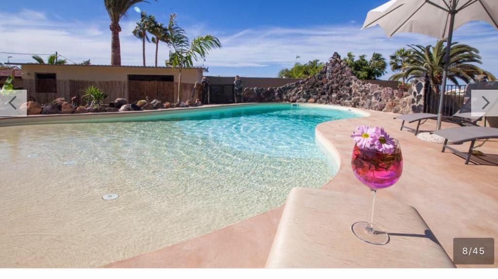帕莱索海滩Paraiso villas的坐在游泳池旁的一杯葡萄酒