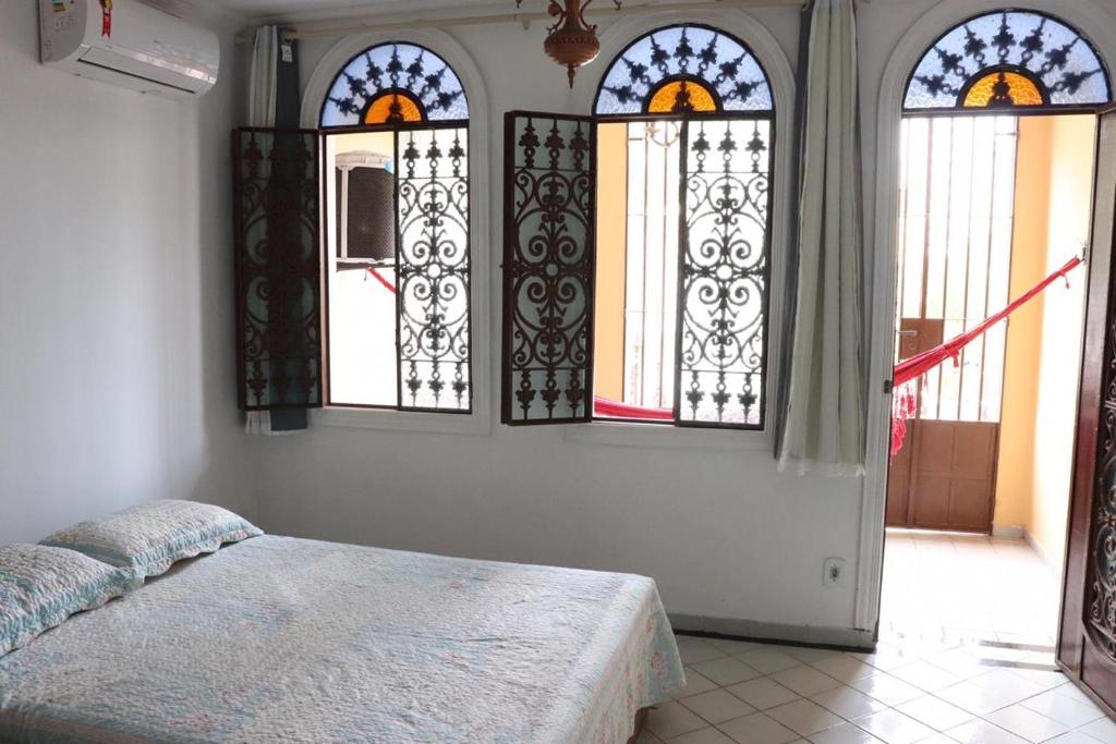 马塞约Casa da Josi - Pajuçara的一间卧室设有三扇彩色玻璃窗和一张床