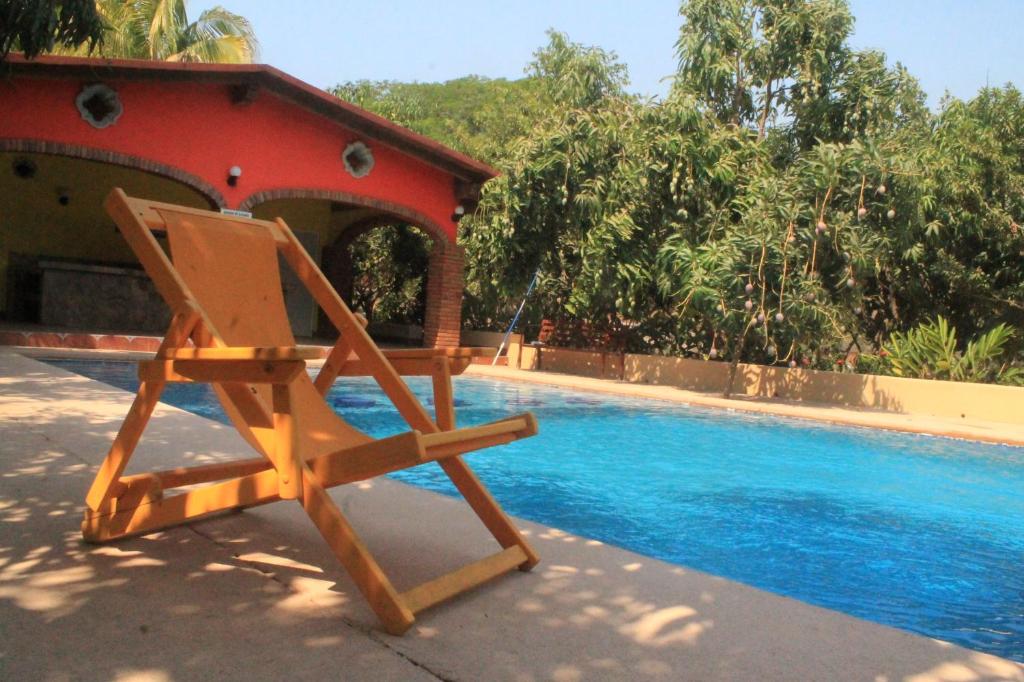 ComalaQuinta Comala Hotel & Villas的一张木椅,位于游泳池旁