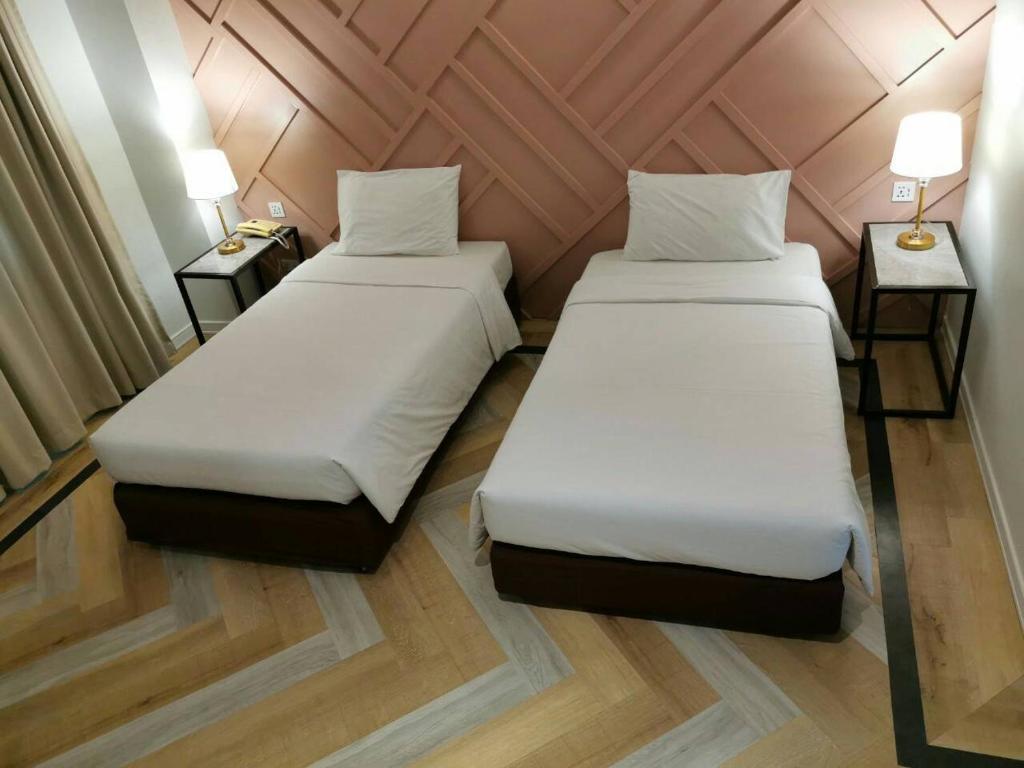 乌汶丽晶乌汶酒店 的配有两盏灯的小房间内的两张床
