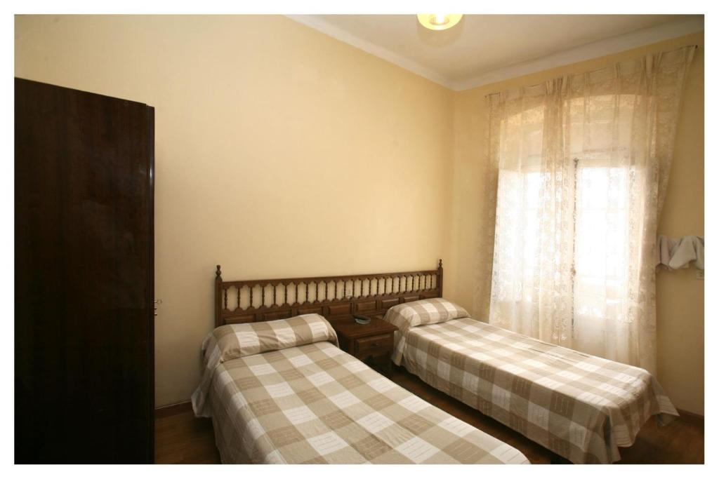 里瓦德奥Hostal Galicia的带窗户的客房内的两张床
