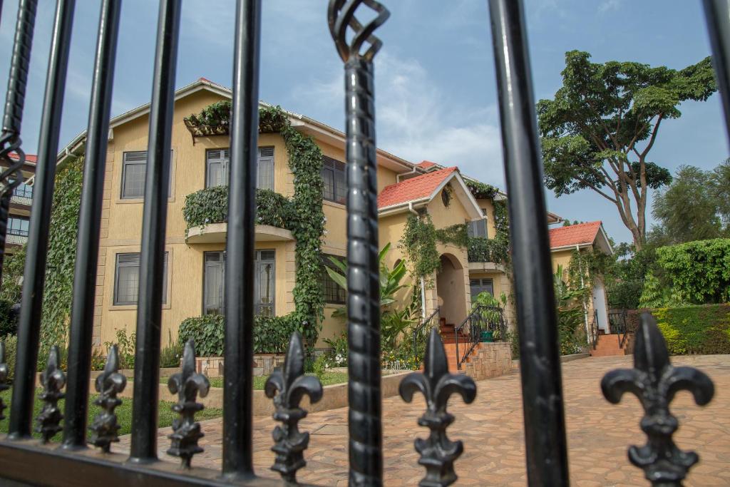 坎帕拉Villa Karibu Serviced Apartments-Kampala的前面有栅栏的黄色房子