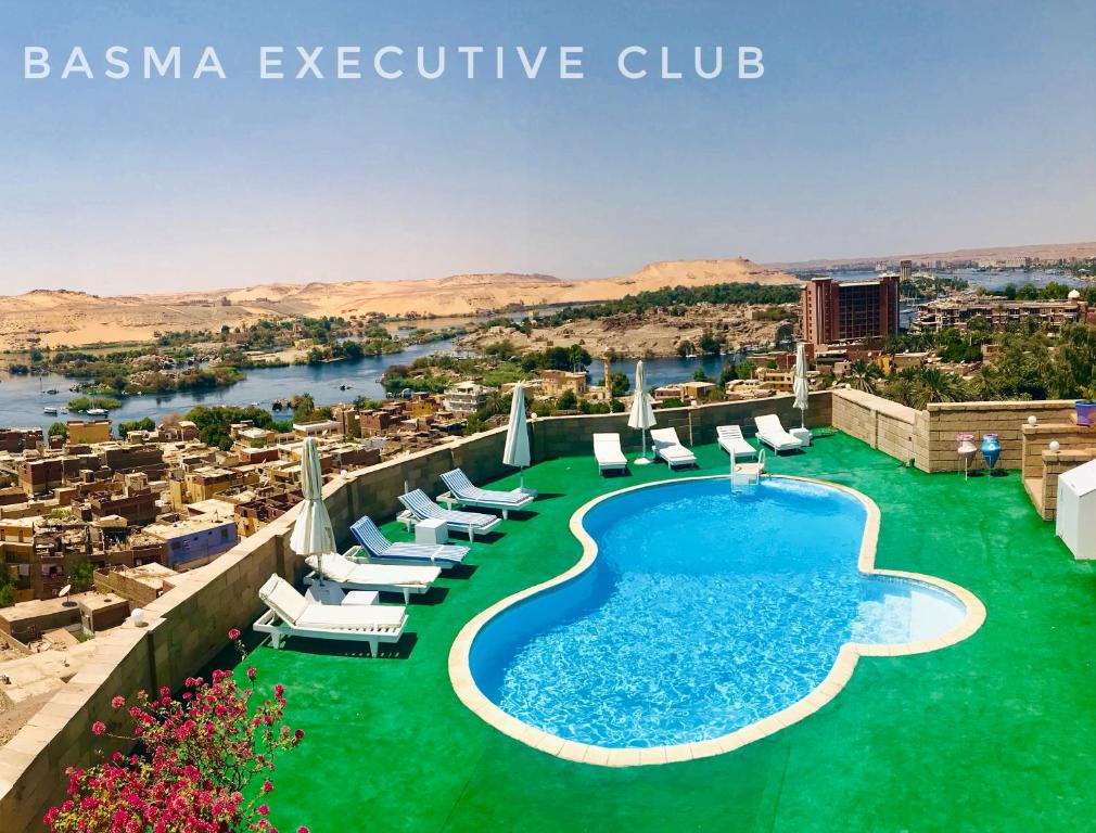 阿斯旺Basma Club的一座带游泳池和椅子的度假村和一个城市