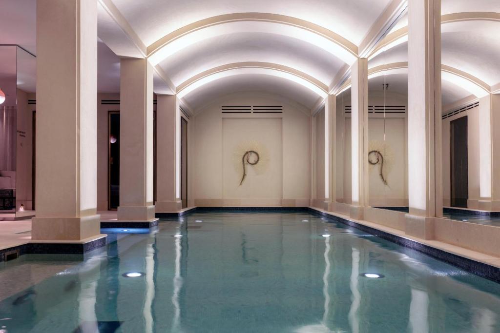 巴黎Les Jardins du Faubourg Hotel & Spa by Shiseido的一座有柱子和水的建筑中的游泳池