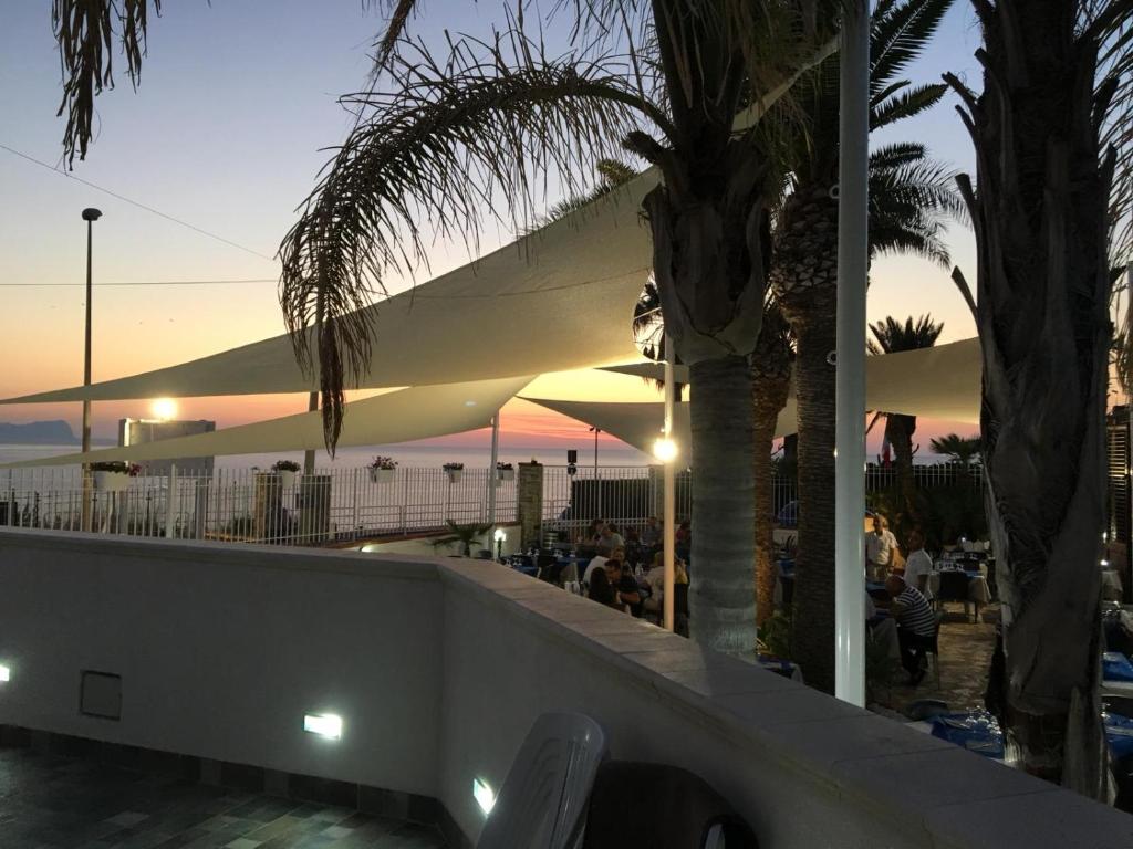泰拉西尼La Ruota B&B的日落时分在海滩上的餐厅,种有棕榈树