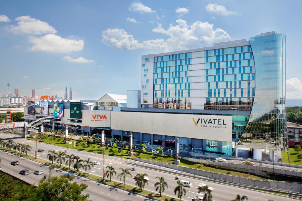 吉隆坡吉隆坡维瓦特尔酒店的一座大型玻璃建筑,前面有一条公路