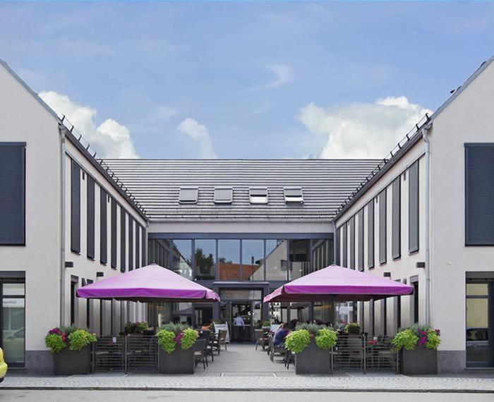 盖森费尔德KH餐厅酒店的一座带紫色雨伞和桌椅的建筑