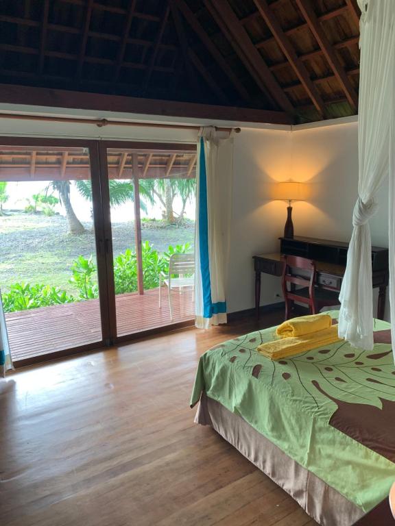 Afaahiti普纳提村庄酒店的一间卧室配有一张床、一张书桌和一个窗户。