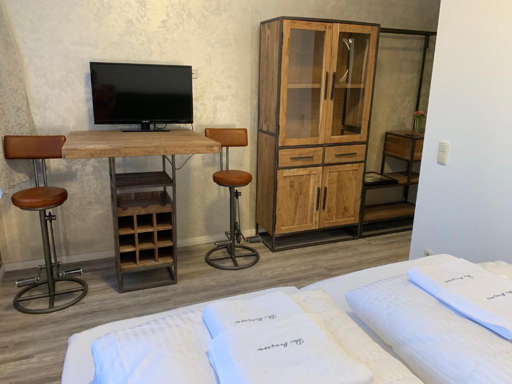 吕贝克Haus 8的一间卧室配有一张床、一台电视和一张带凳子的桌子。