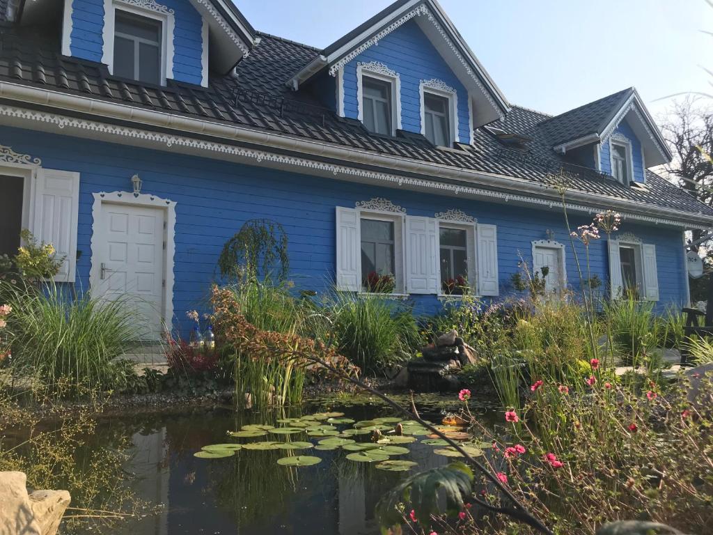 比亚沃维耶扎Pensjonat Krainka的蓝色的房子,前面有一个池塘