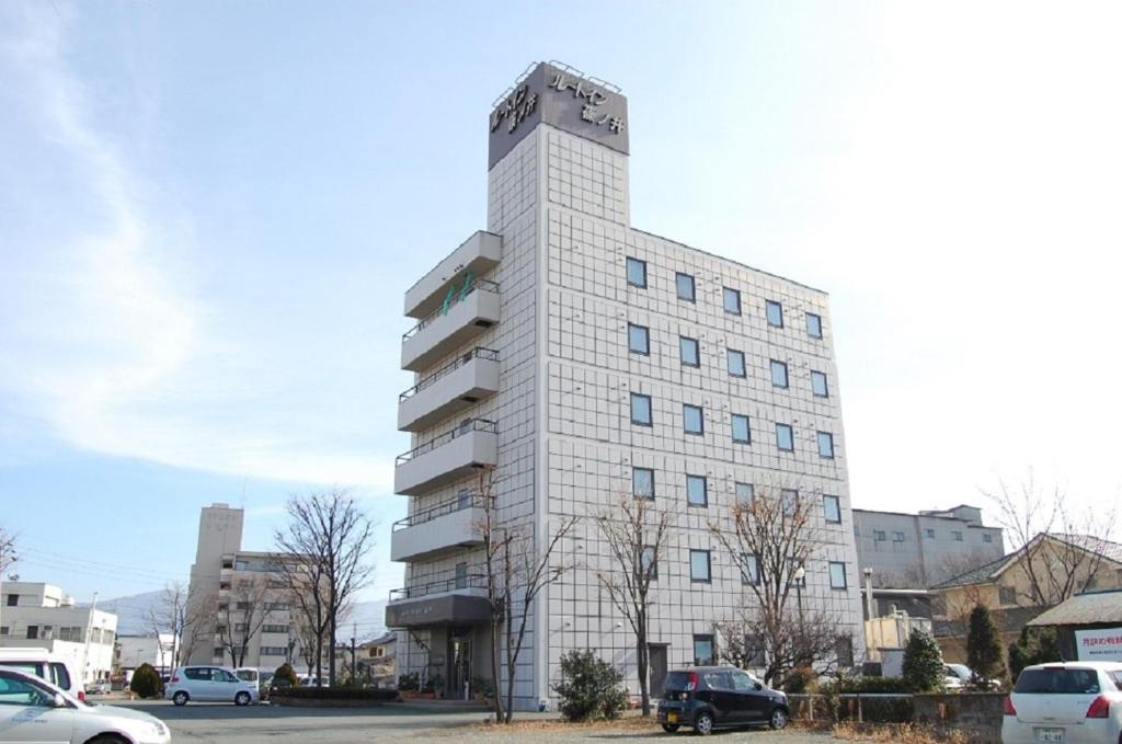长野筱之井如特酒店的一座高大的白色建筑,汽车停在停车场
