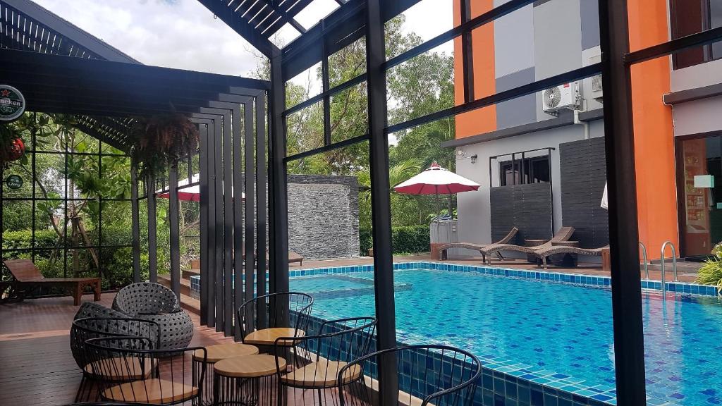 巴吞他尼Baan Bangkok 97 Hotel的一座带桌椅的游泳池位于酒店大楼旁