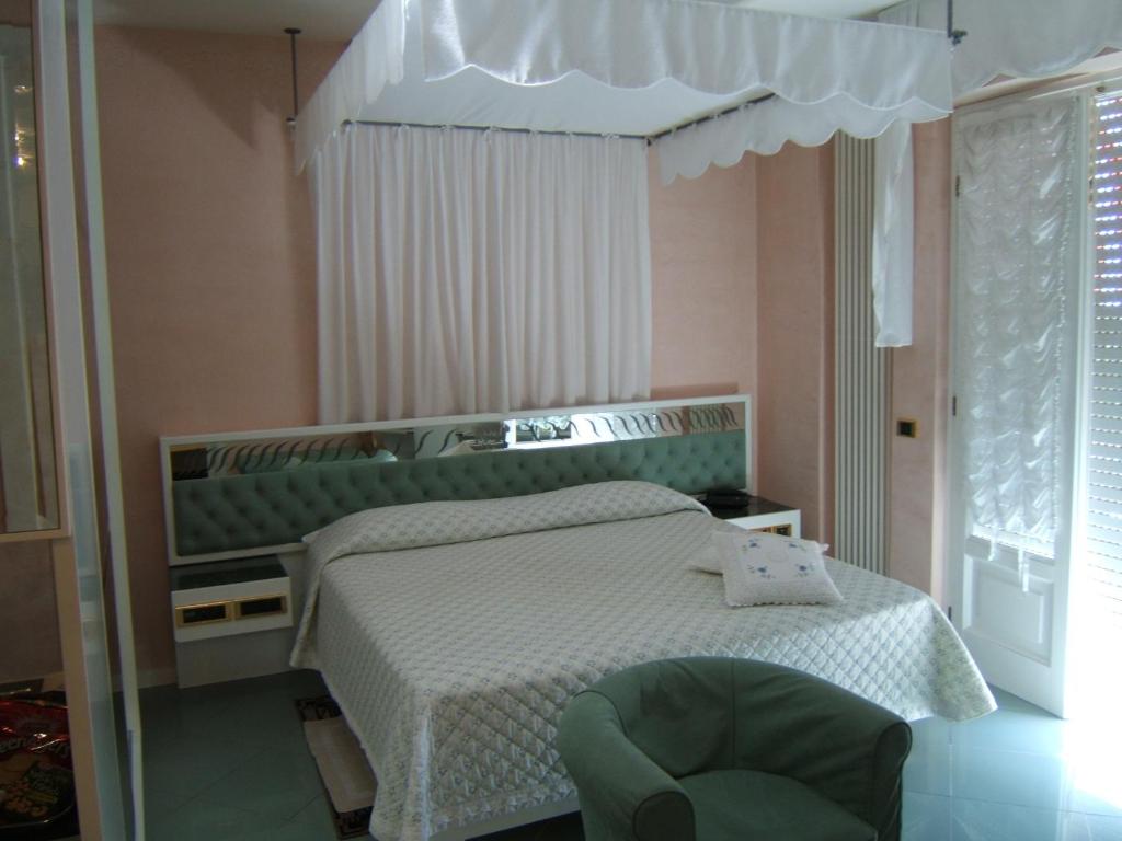 马里纳迪马萨马蒂尔德酒店的一间卧室配有一张床和一把绿色椅子