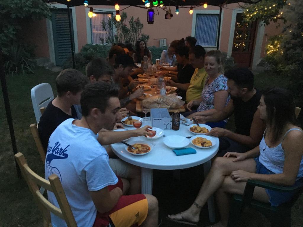 布达佩斯Balázs Guesthouse的一群坐在桌子旁吃食物的人