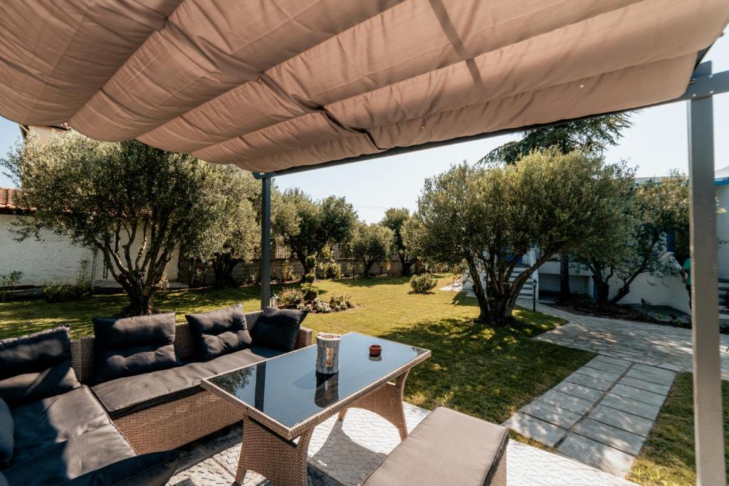 尼坡帝Cyclades Luxury Studios的一个带沙发和大伞下桌子的庭院