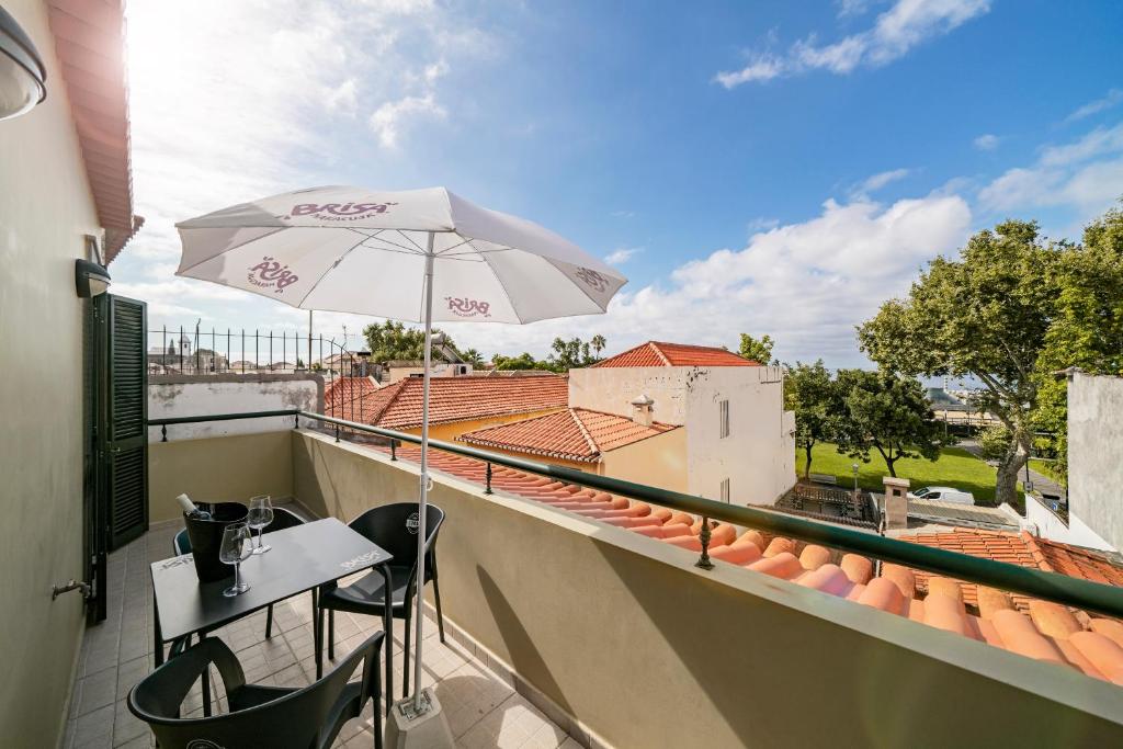 丰沙尔OurMadeira - Taberna Apartments, old town的阳台的天井配有桌子和遮阳伞。