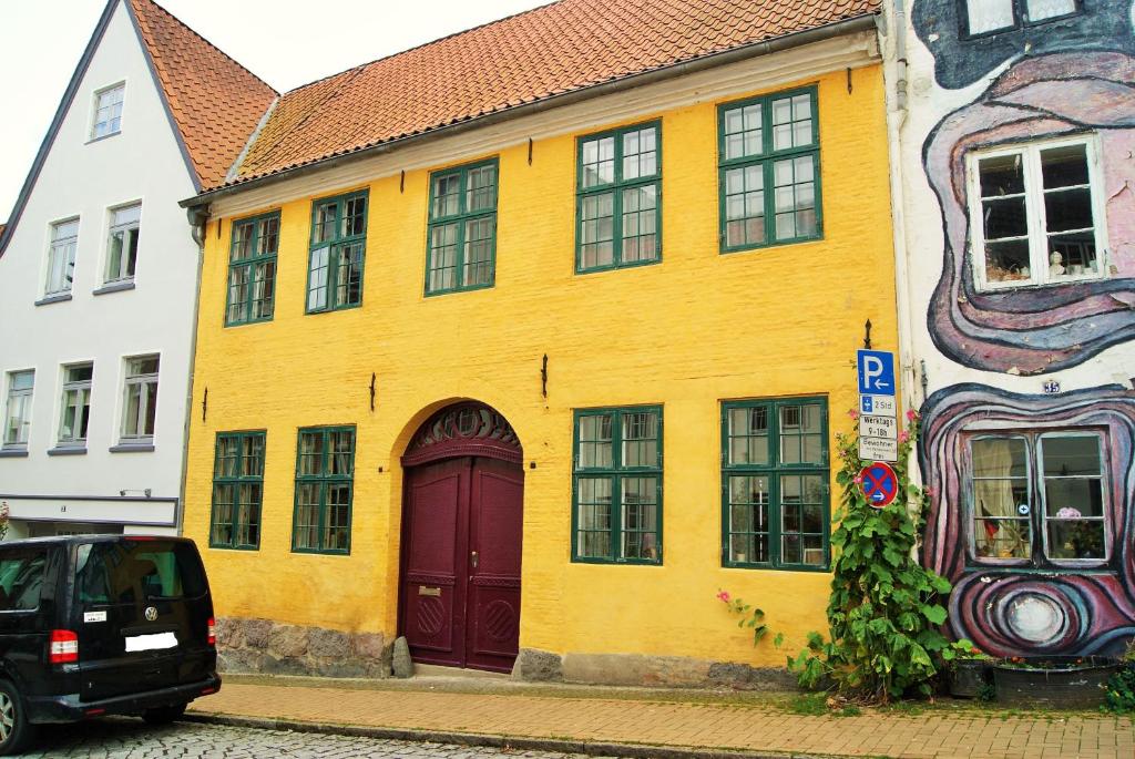 弗伦斯堡Das Gelbe Haus - Drei besondere Ferienwohnungen的街上有黄色的建筑,有红色的门