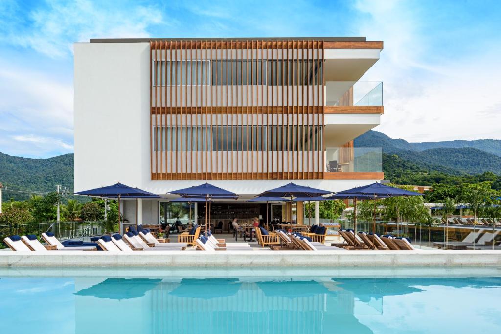 安格拉杜斯雷斯Hotel Fasano Angra dos Reis的一座带椅子和遮阳伞的游泳池位于一座建筑旁边
