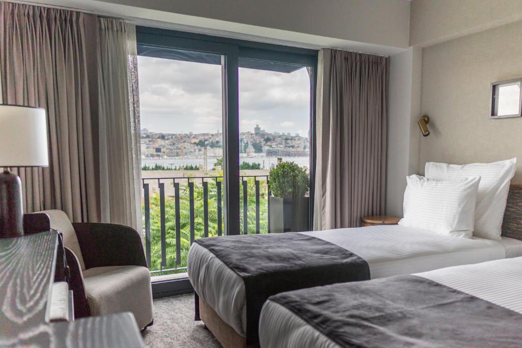 伊斯坦布尔MEG HOTEL的酒店客房设有两张床和一个阳台。