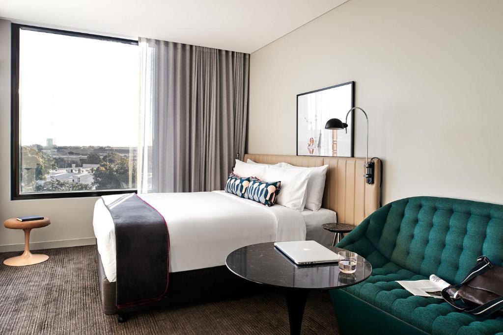 悉尼Veriu Green Square的酒店客房,设有一张床铺和一张绿色沙发