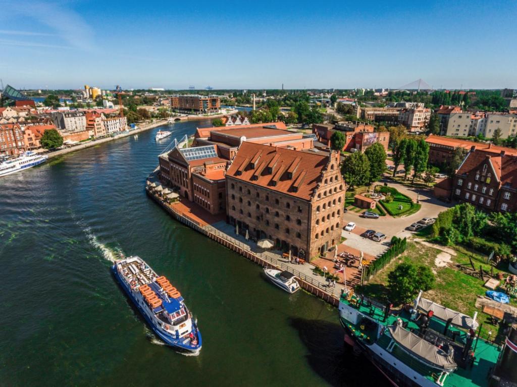 格但斯克Jess Hotel Krolewski Gdansk Old Town的船停靠在城市的河流上