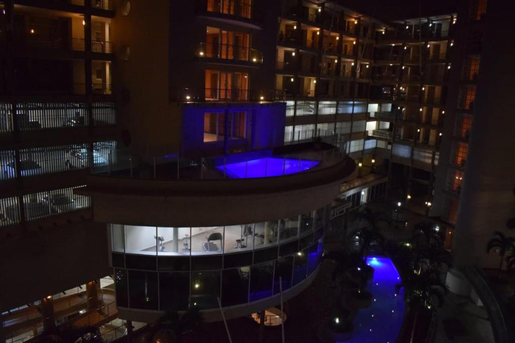 德班Two bedroom apartment at the Sails的享有大楼的夜间景色,设有蓝色的游泳池