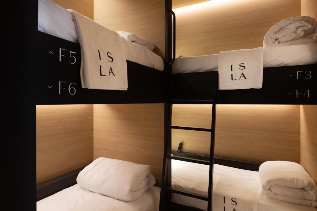 特拉维夫ISLA Tel Aviv的客房设有2张双层床和白色枕头。