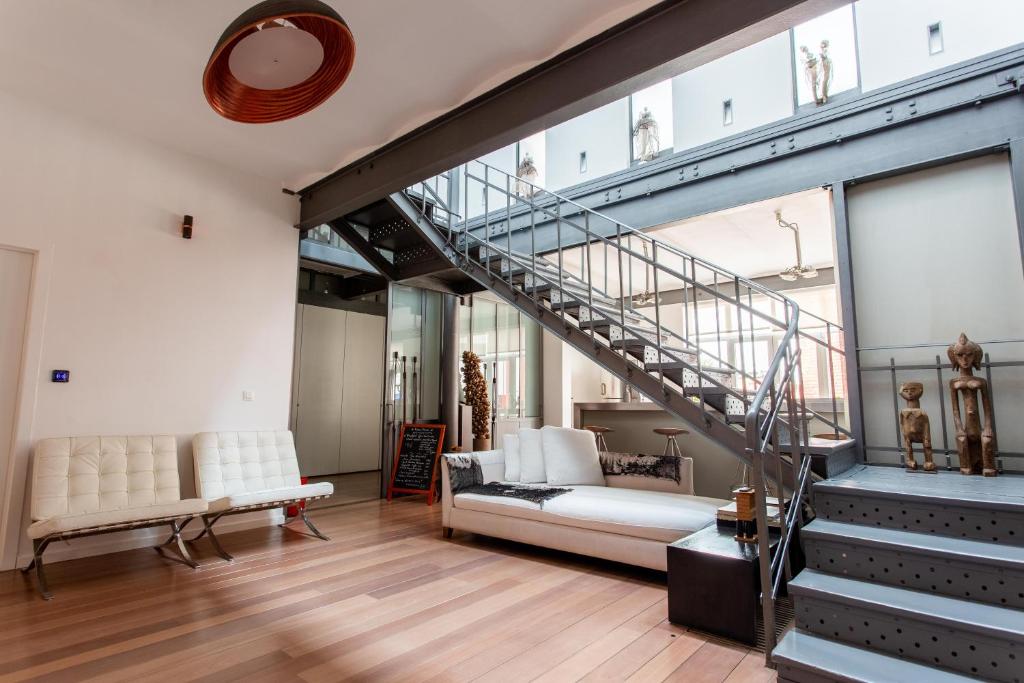 布鲁塞尔Les Lofts d'Artistes的一间带楼梯和沙发的客厅