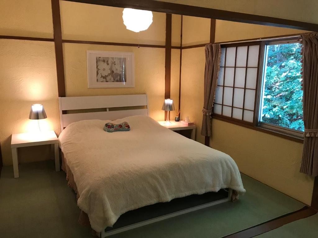 汤泽町Naeba Ski Resort & Fuji Rock的一间卧室配有一张大床、两张桌子和一扇窗户